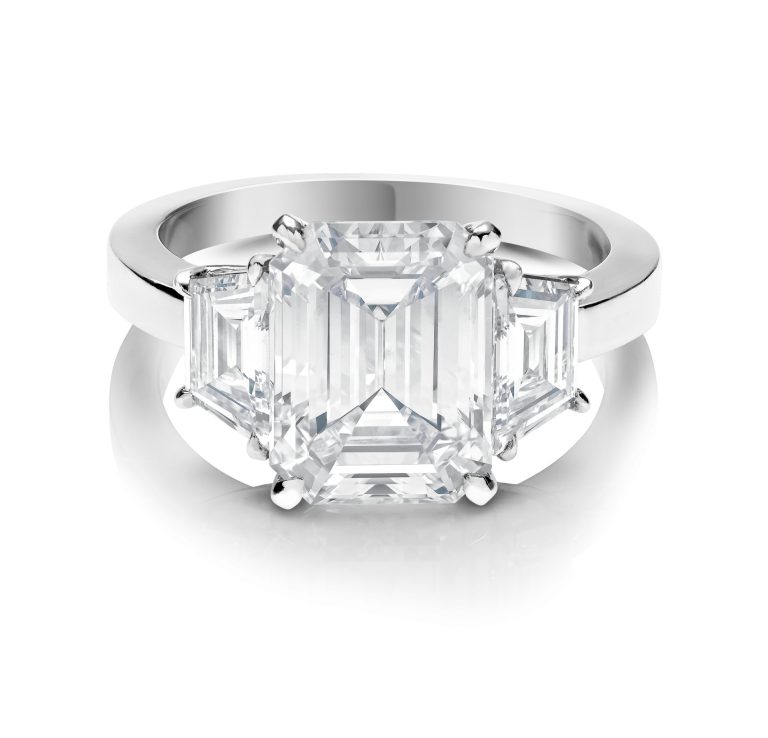Anillo de compromiso con diamante corte esmeralda y dos diamantes a los lados, montados en platino. (MODELO 41039R)